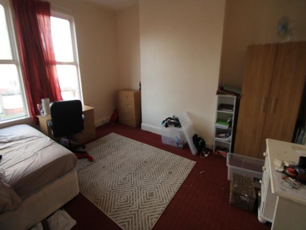 A modest bedroom with a single bed, a study des...