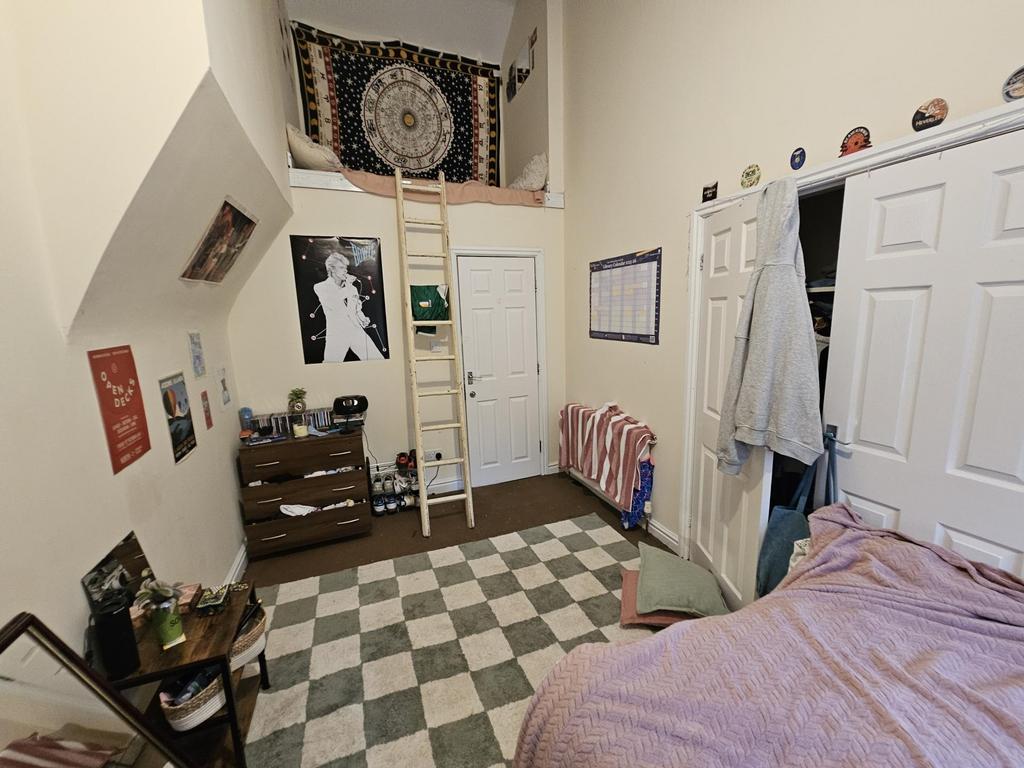 A cozy bedroom featuring a bed with a pink cove...