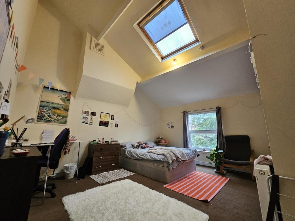 A cozy and well-lit student bedroom featuring a...