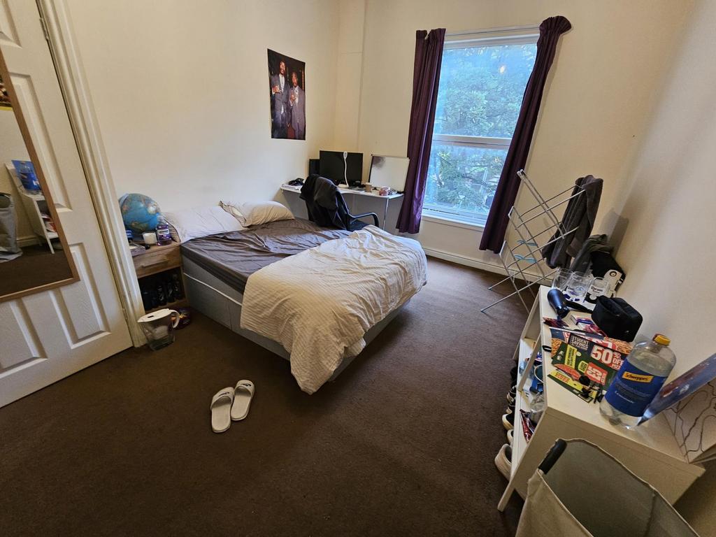 A cozy bedroom featuring a double bed, a window...