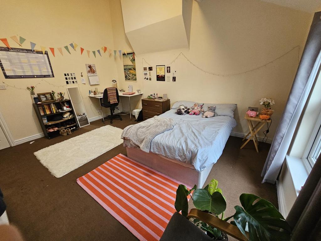 A cozy bedroom featuring a double bed with a li...