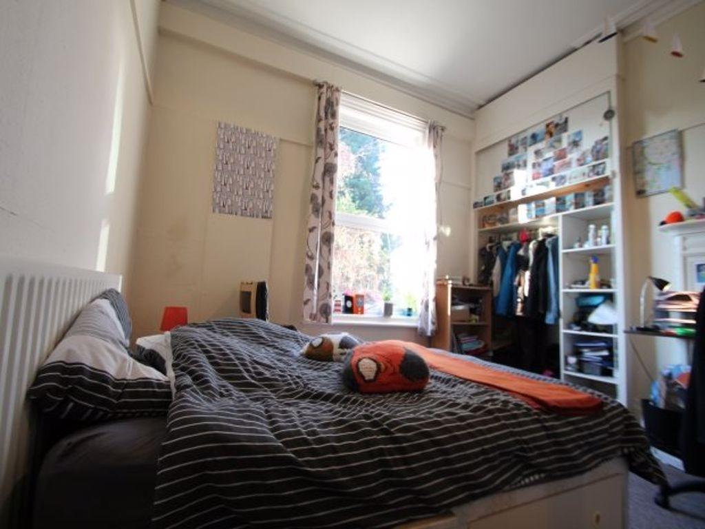 A cozy bedroom featuring a bed with striped bed...