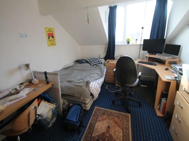 A cozy bedroom featuring a single bed, a desk w...