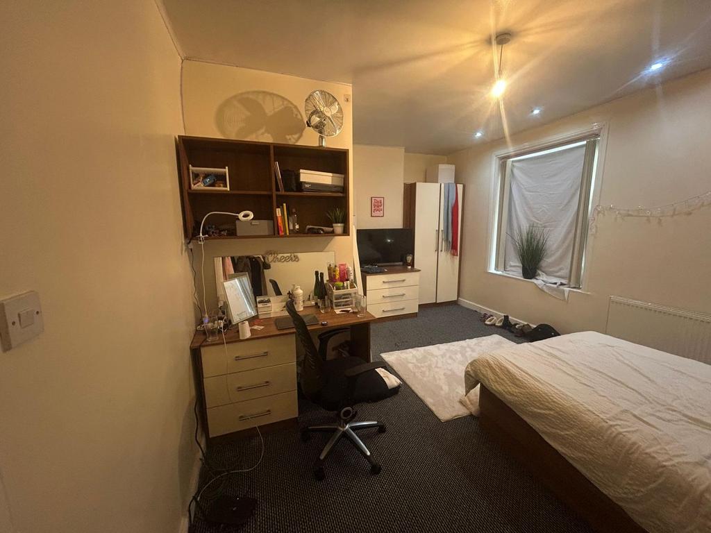 A cozy bedroom featuring a single bed, a desk w...