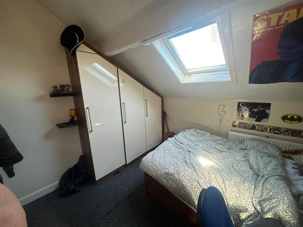 A cozy bedroom featuring a bed, wardrobe, and a...