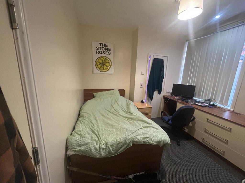 A tidy bedroom featuring a bed with a light gre...