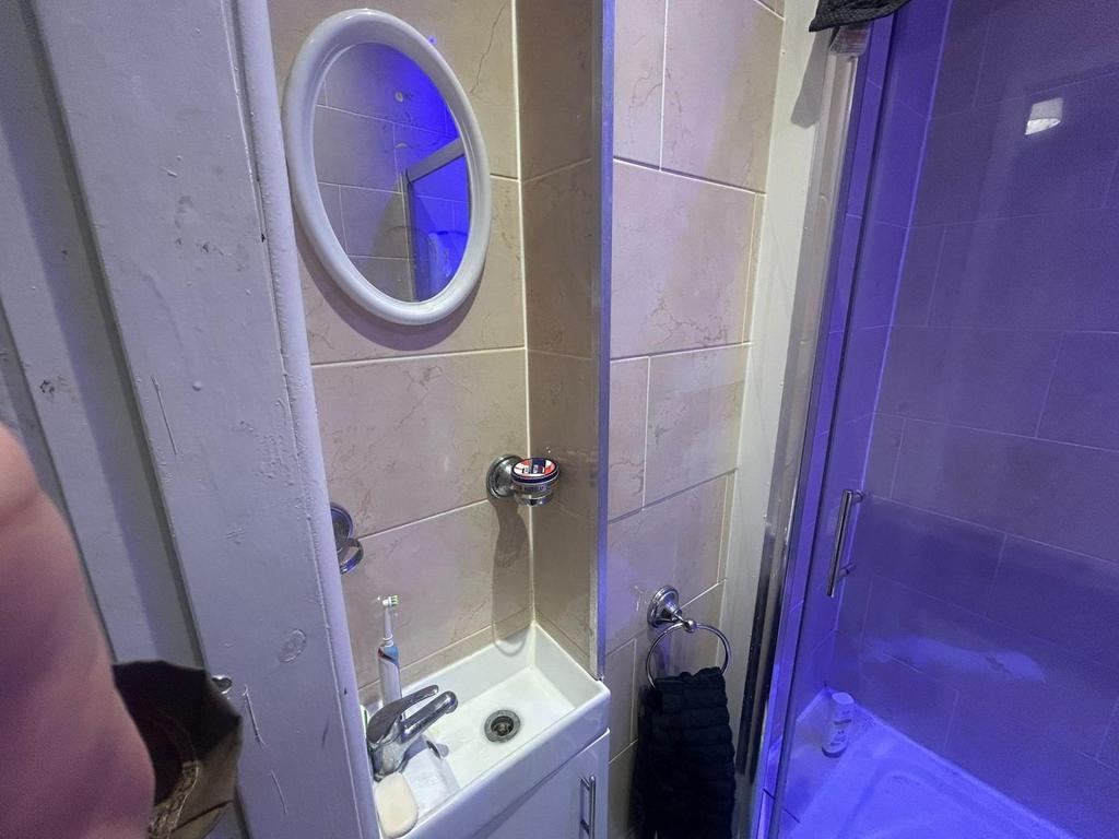 A compact bathroom featuring a small sink, mirr...