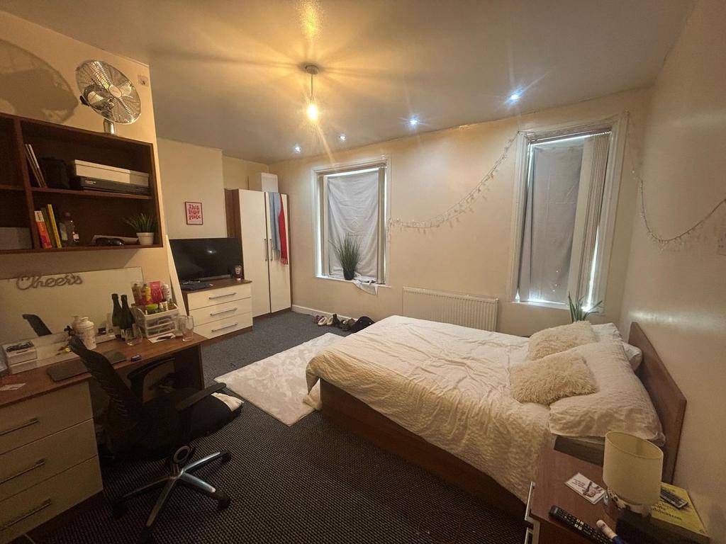 A well-lit bedroom featuring a double bed and a...