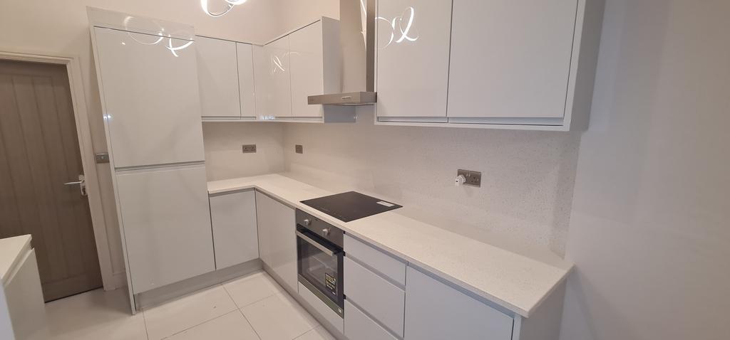 A modern, bright kitchen featuring white cabine...