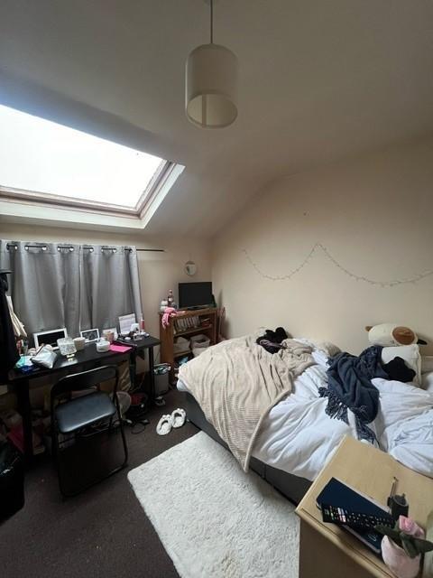 A cozy bedroom with a sloped ceiling illuminate...