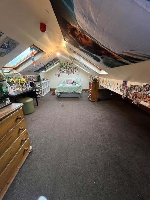 A cozy bedroom with a single bed, well-lit with...