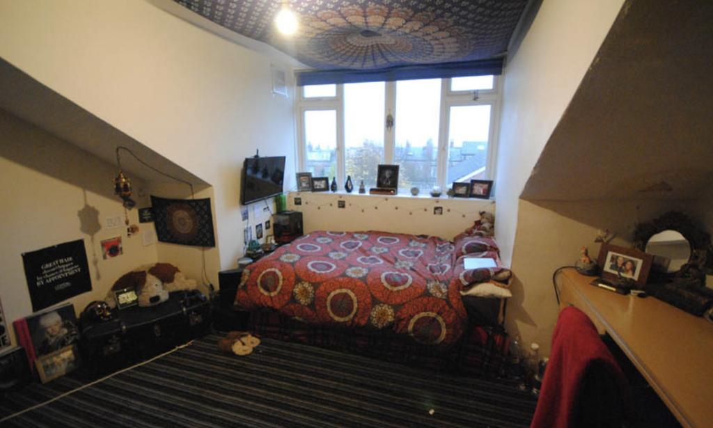 A cozy single bedroom featuring a double bed, d...