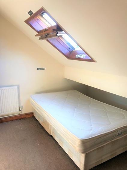 A cozy single bedroom with a sloped ceiling fea...