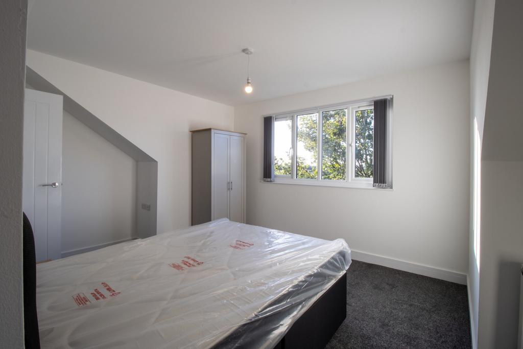 A bright and tidy bedroom with a large window l...