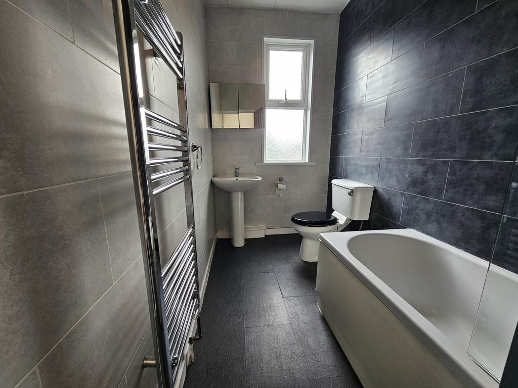 Modern bathroom featuring a clean white bath, t...