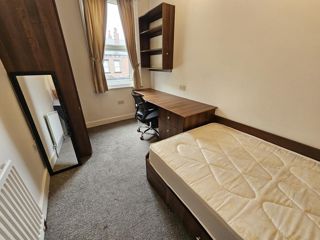 A neat, well-lit single bedroom featuring a des...