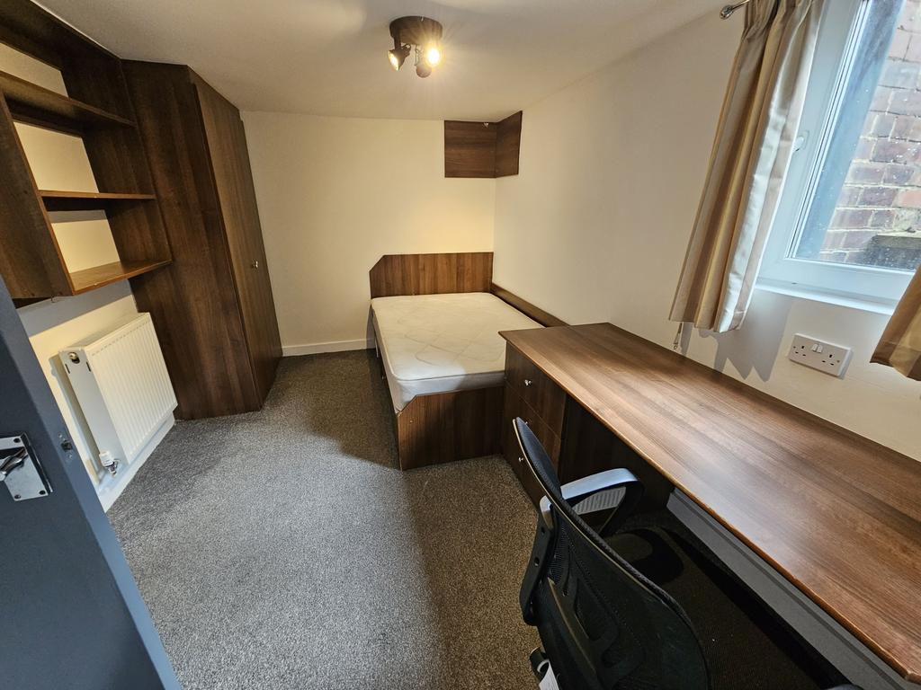 A cozy and well-organized single bedroom featur...