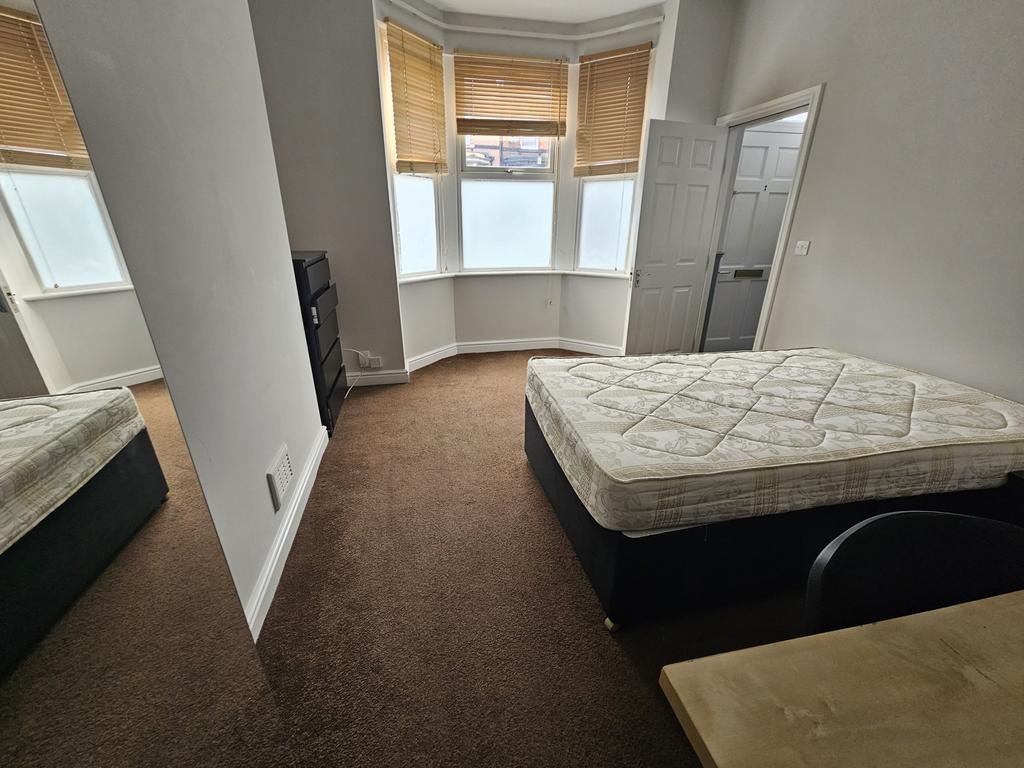A spacious bedroom with a large window allowing...