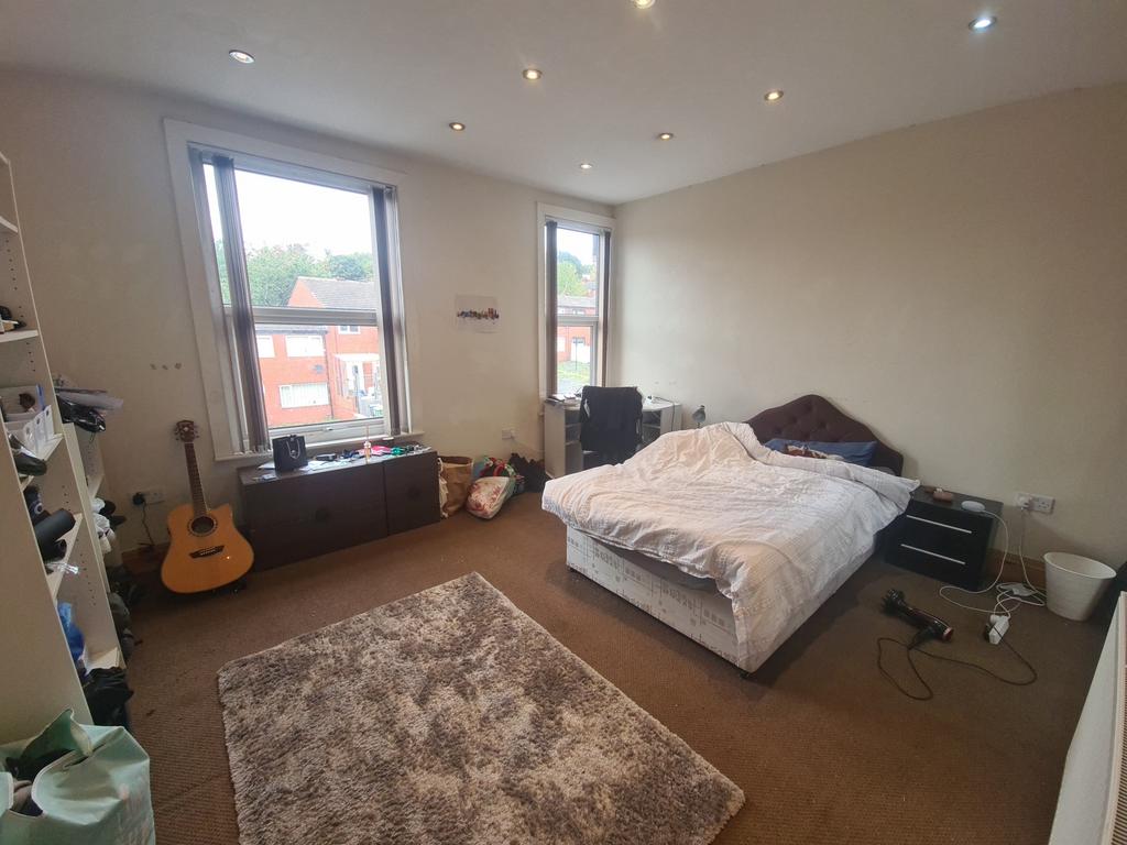 A spacious master bedroom well-lit by large win...