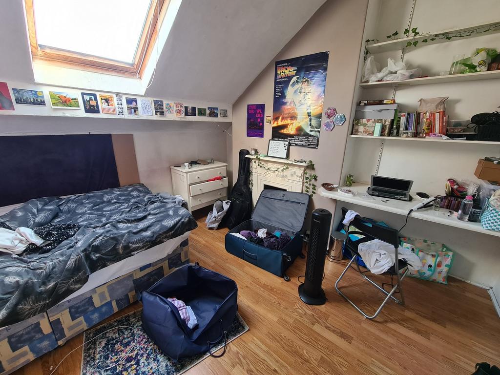 A well-lit bedroom featuring a single bed, work...