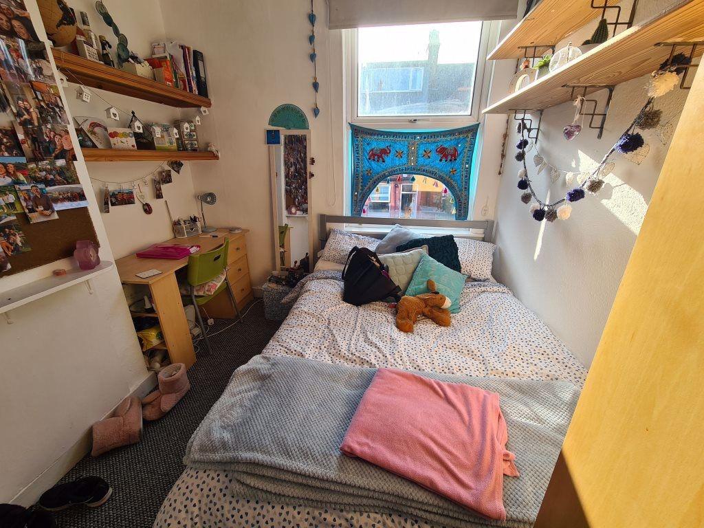 A cozy, well-lit single bedroom featuring a com...