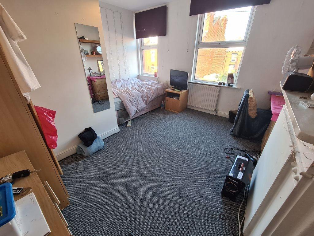 A modest bedroom featuring a bed, window with n...