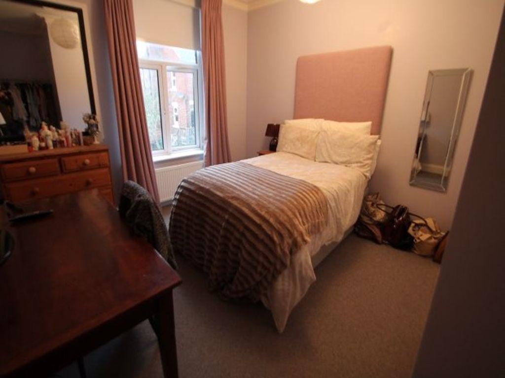 A cozy student bedroom featuring a single bed w...