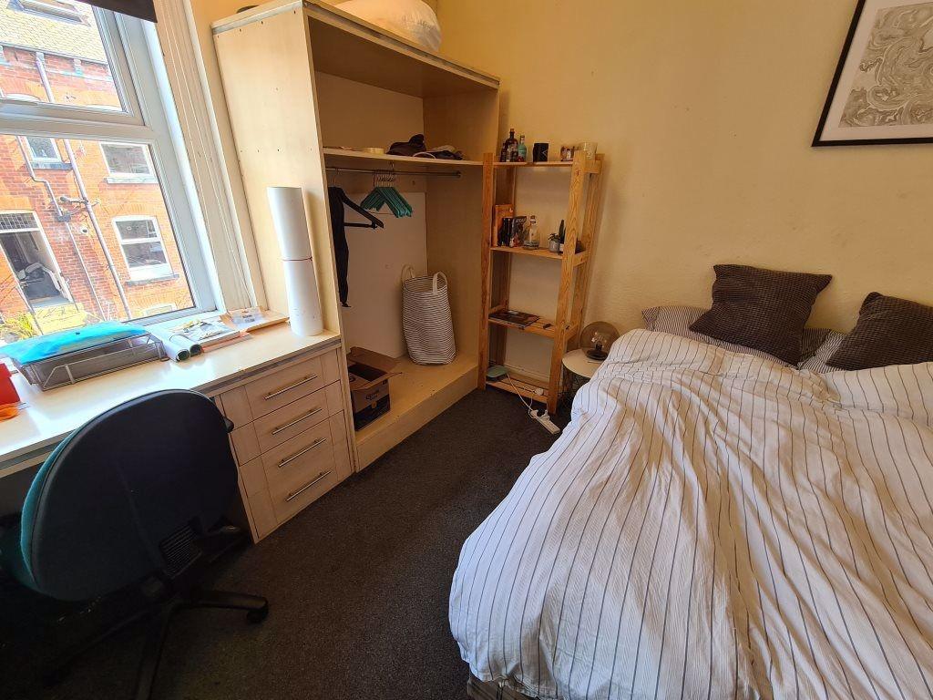 A cozy single bedroom with a neatly made bed, a...