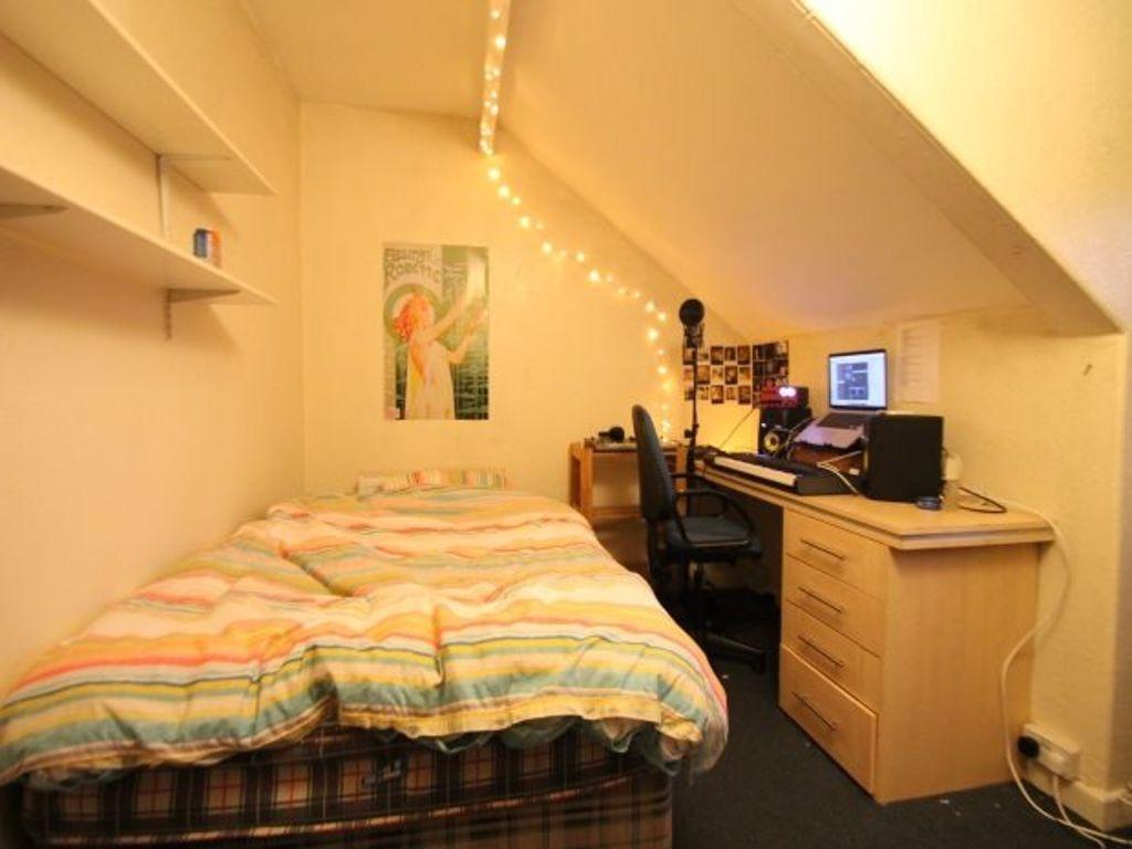 A cozy bedroom with a neatly made bed featuring...