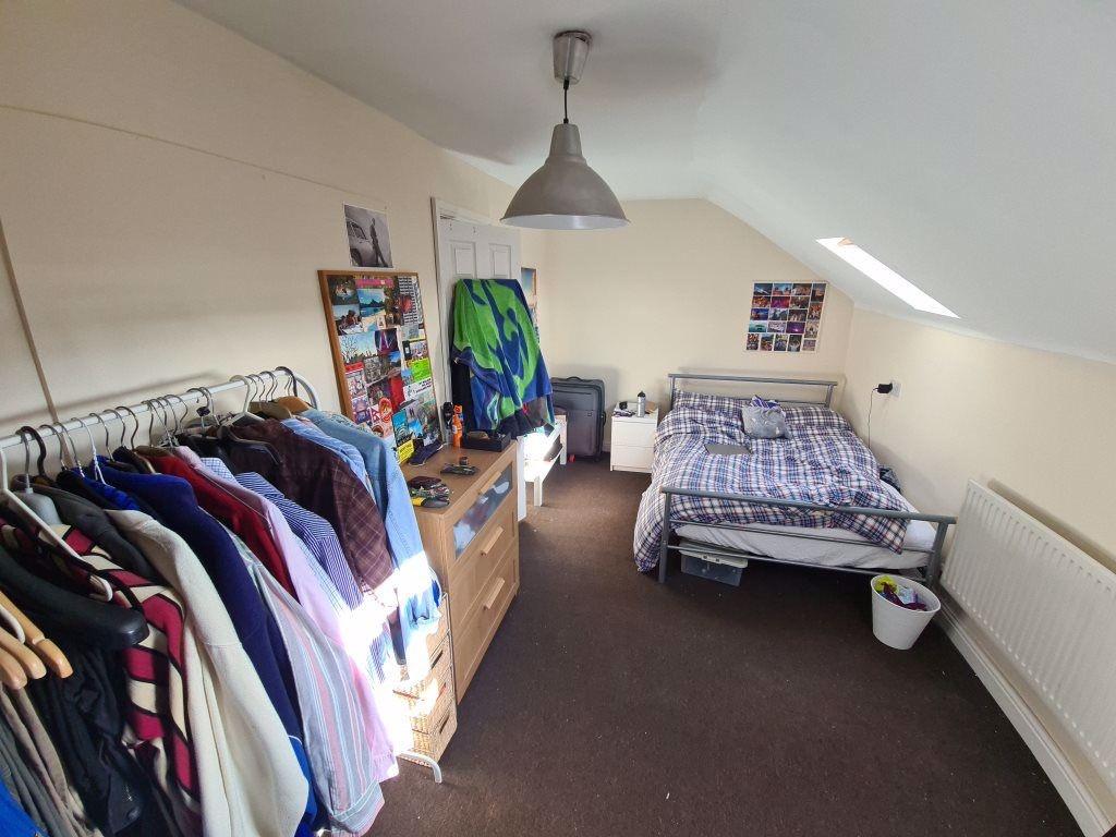 A well-lit bedroom with a neatly made bed, ampl...
