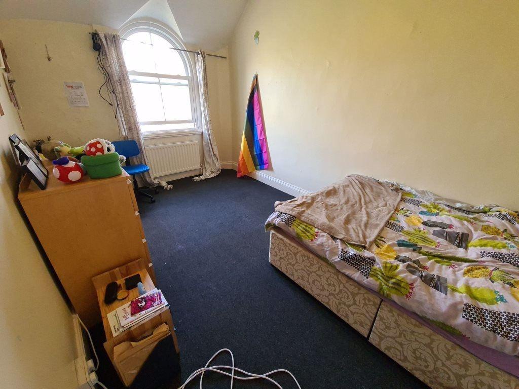 A modest bedroom featuring a single bed with a ...