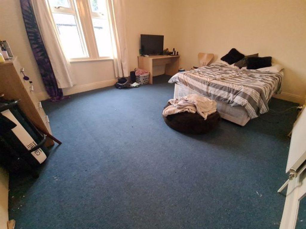 A spacious double bedroom with a neatly made be...