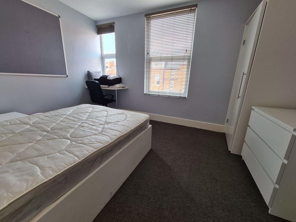 A clean and well-lit single bedroom with a comf...
