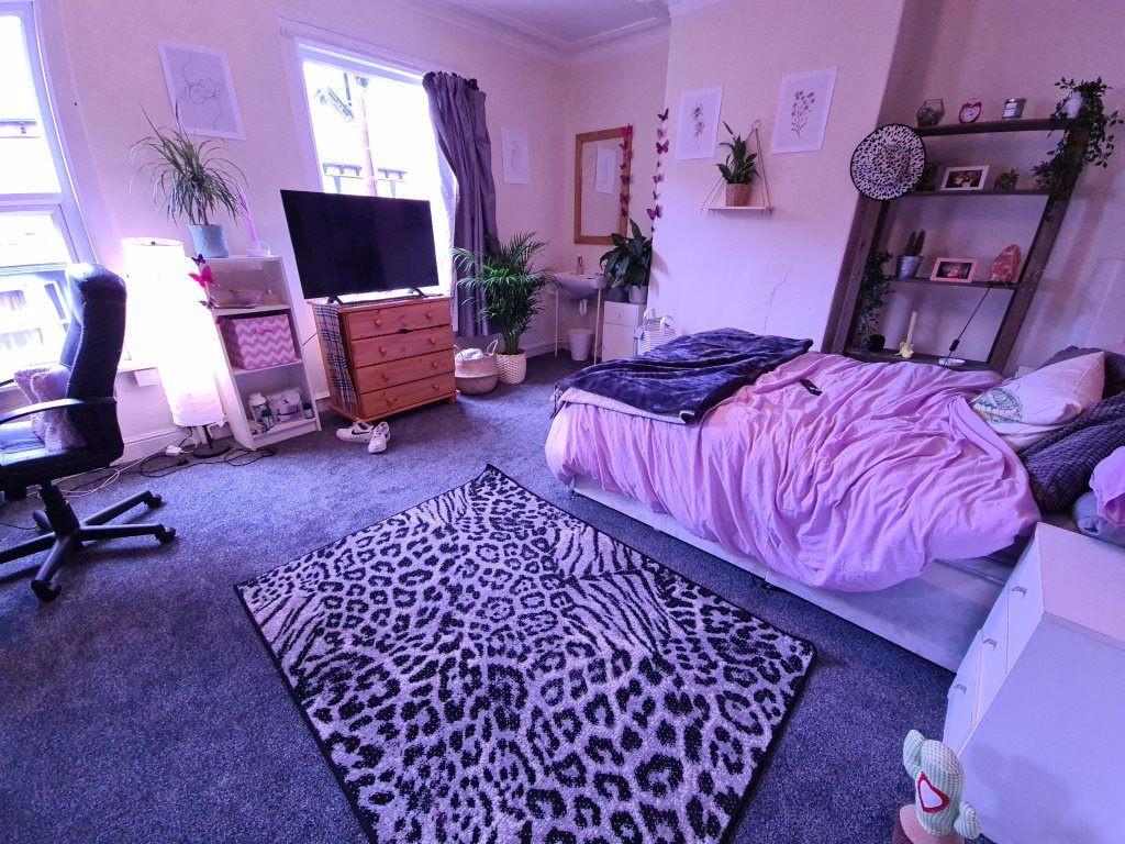 A cozy bedroom featuring a double bed with purp...