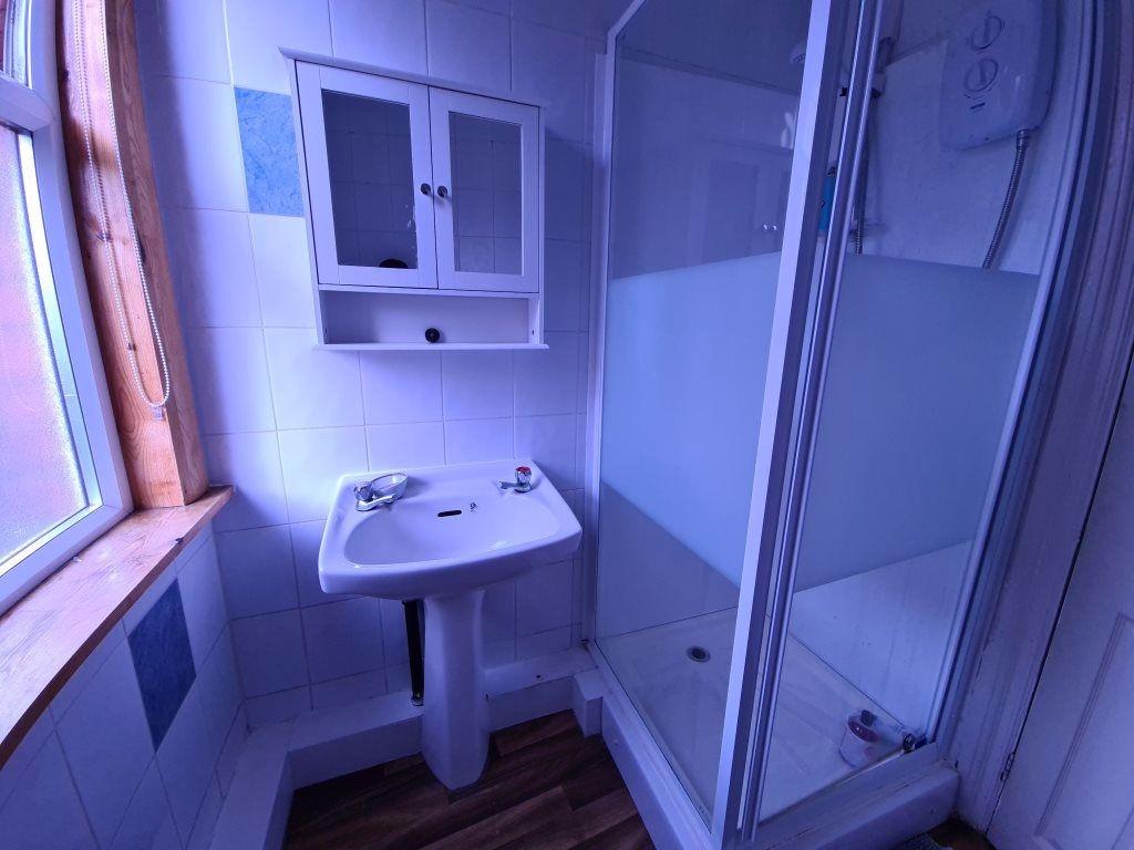 A clean and well-lit bathroom featuring a showe...