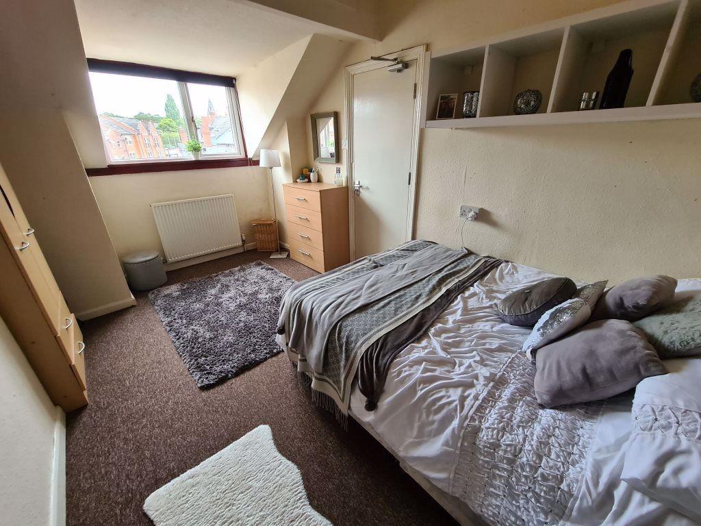 A cozy, well-lit bedroom featuring a comfortabl...