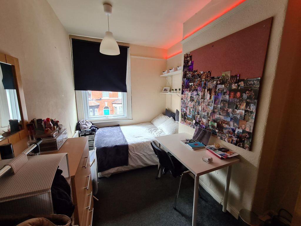 A well-lit and tidy bedroom featuring a comfort...