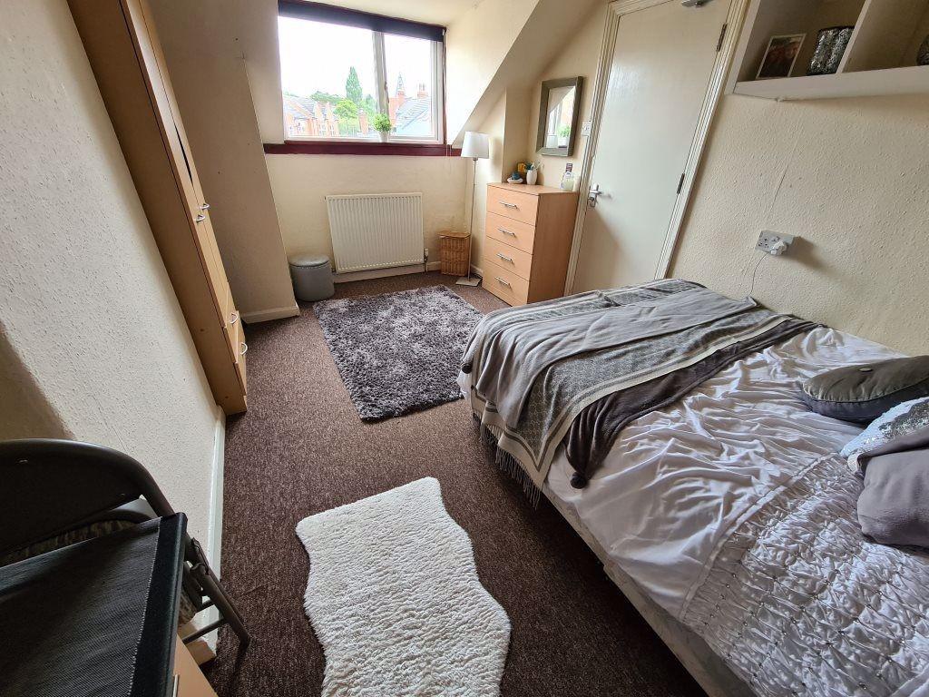 A cozy single bedroom featuring a bed, window w...