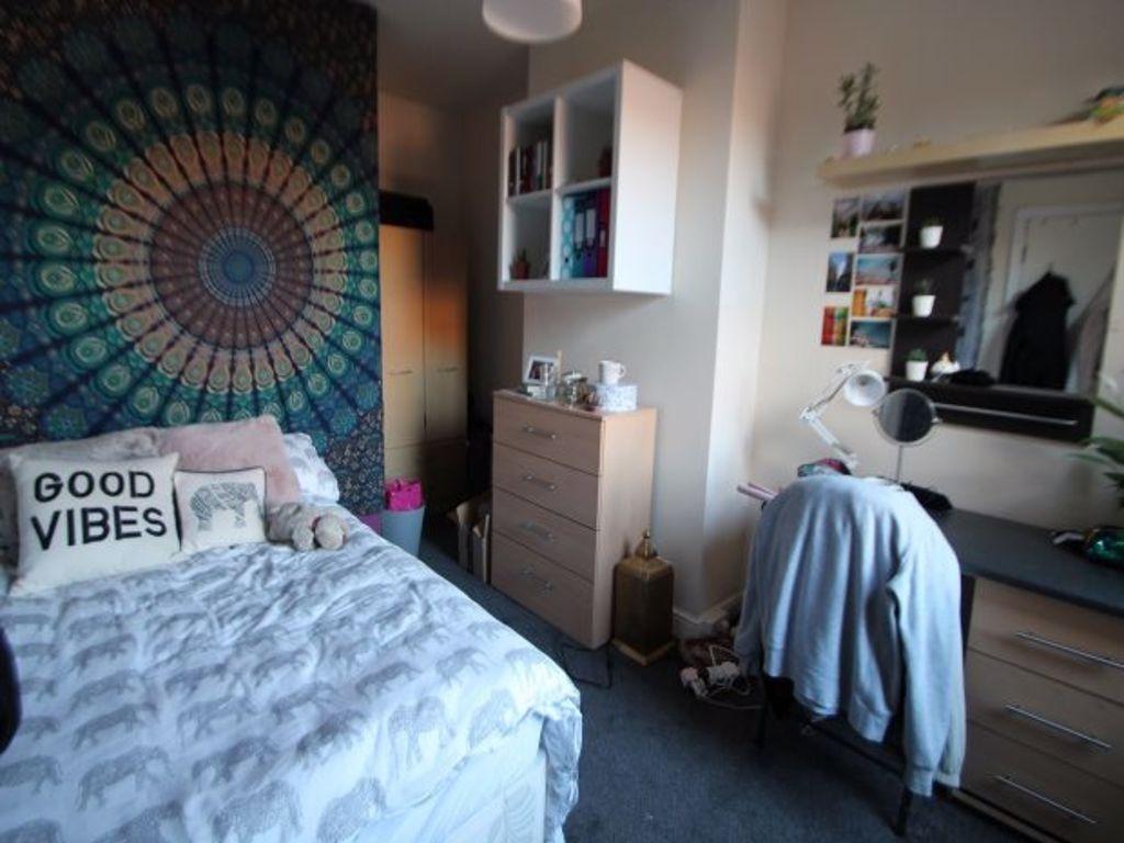 A well-lit bedroom featuring a cozy bed, a ward...