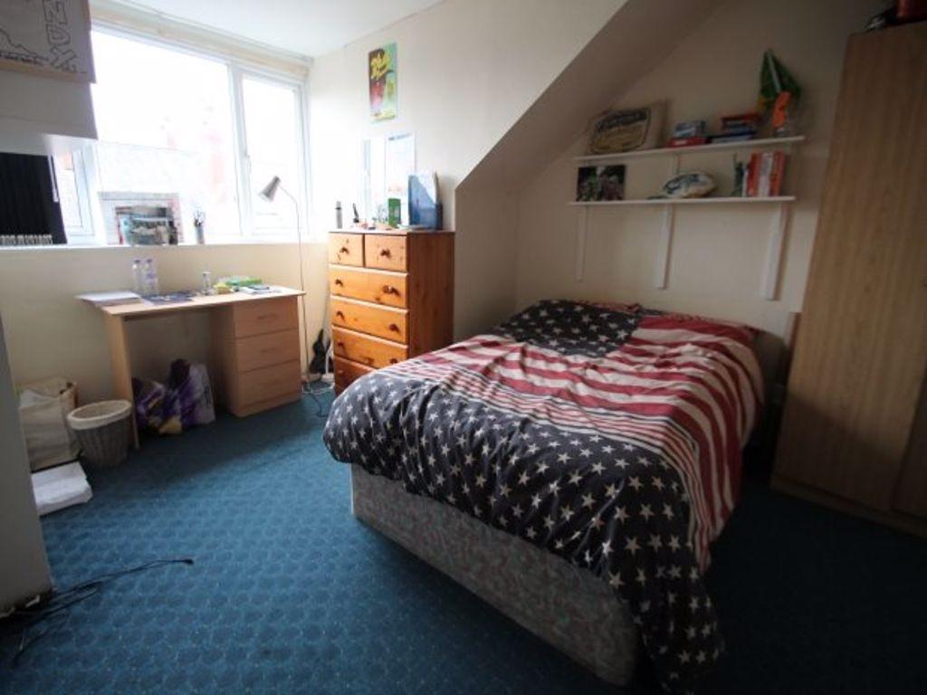 A cozy single bedroom featuring a bed with a pa...