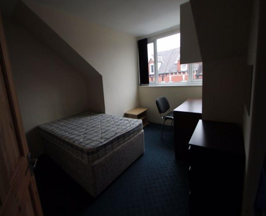 A compact bedroom featuring a single bed under ...