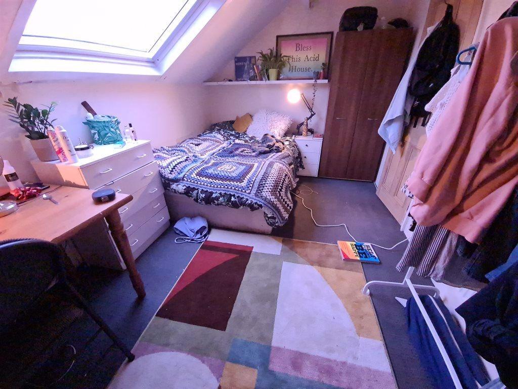 A cozy bedroom featuring a neatly made bed, a d...