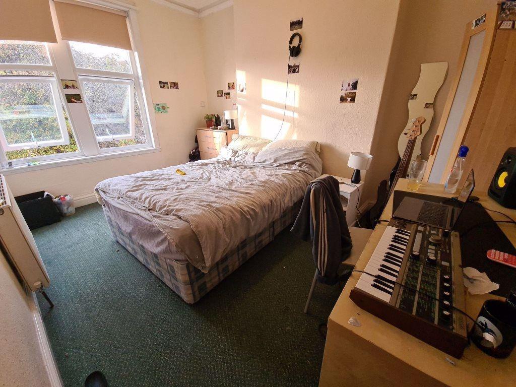 A well-lit double bedroom featuring a cozy bed ...