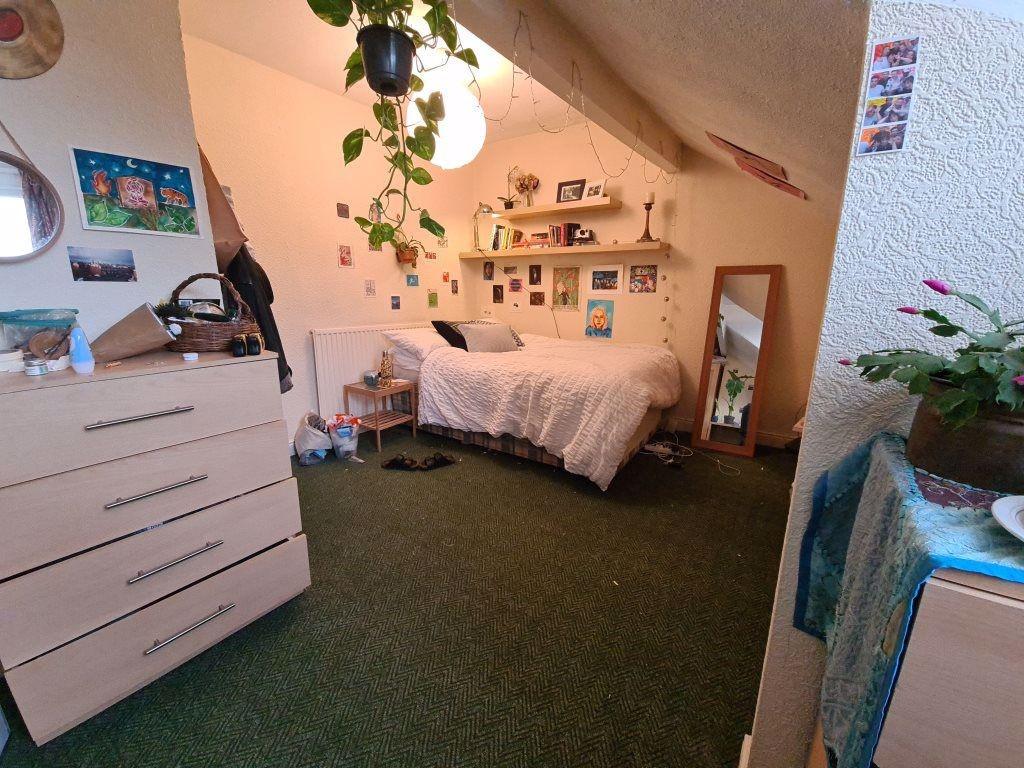 A cozy bedroom featuring a single bed, a storag...