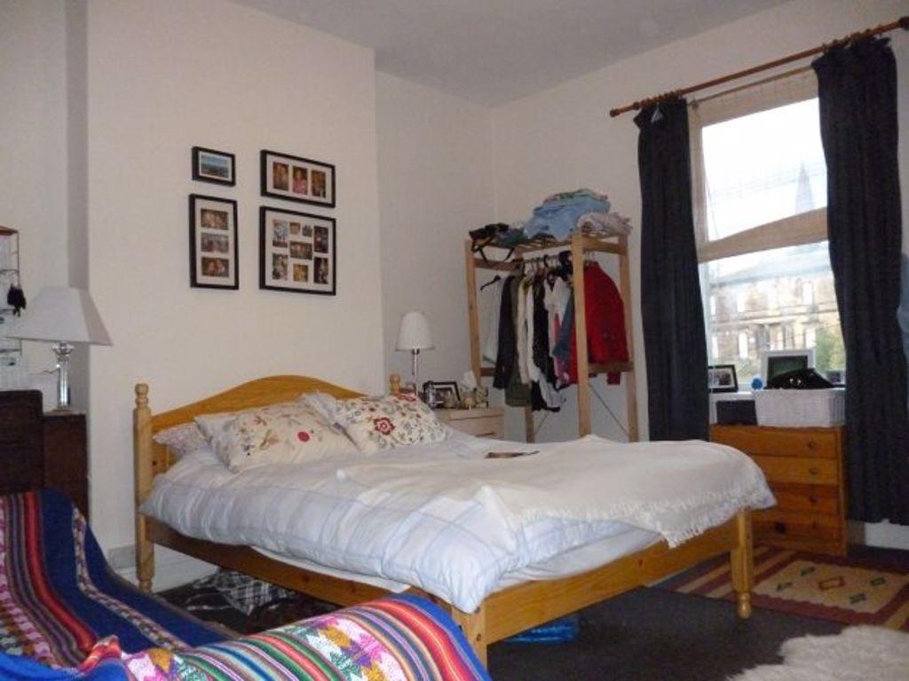 A cozy double bedroom featuring a wooden bed fr...