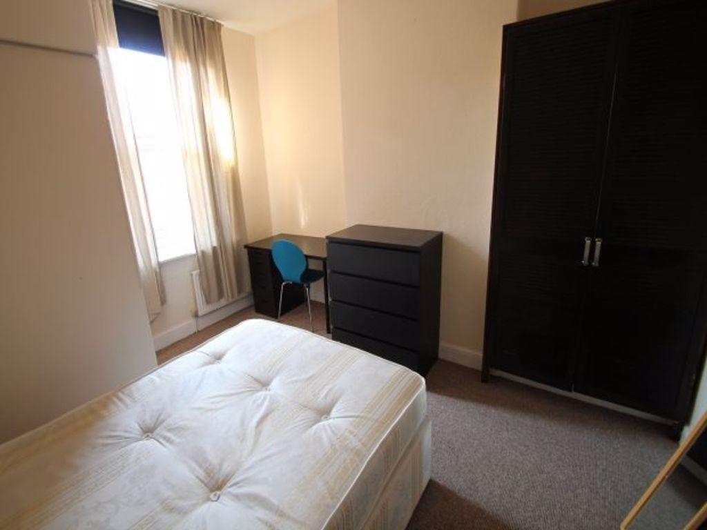 A bright, tidy bedroom with a large bed, a smal...