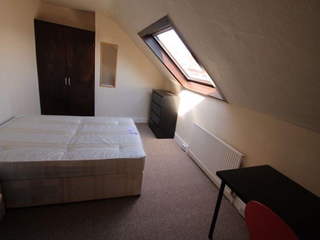 A well-lit bedroom featuring a bed, a window le...