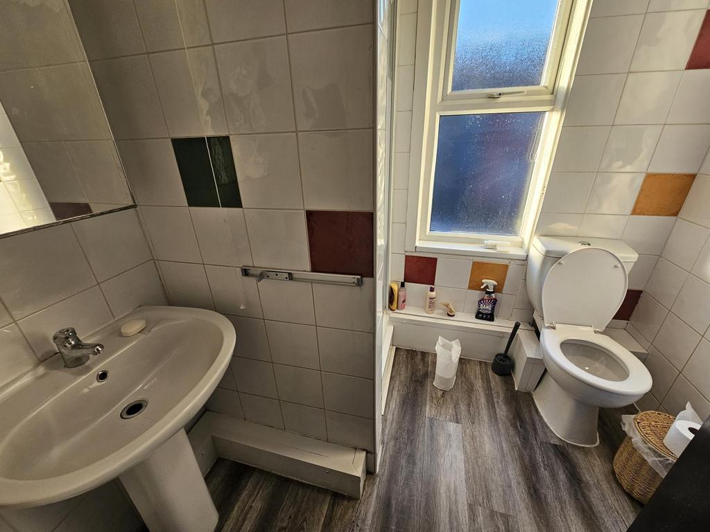 Bright bathroom with a pedestal sink, toilet, f...