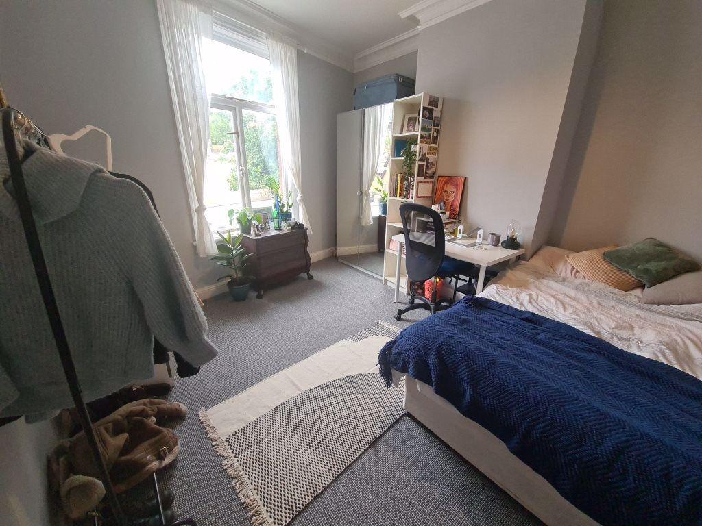 A cozy bedroom featuring a neatly made bed with...