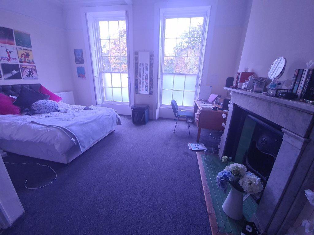 A well-lit bedroom featuring a comfortable bed,...